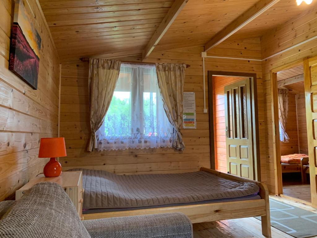 a bedroom in a log cabin with a bed and a window at Zielony Zakątek domki i pokoje 661-038-537 in Polańczyk