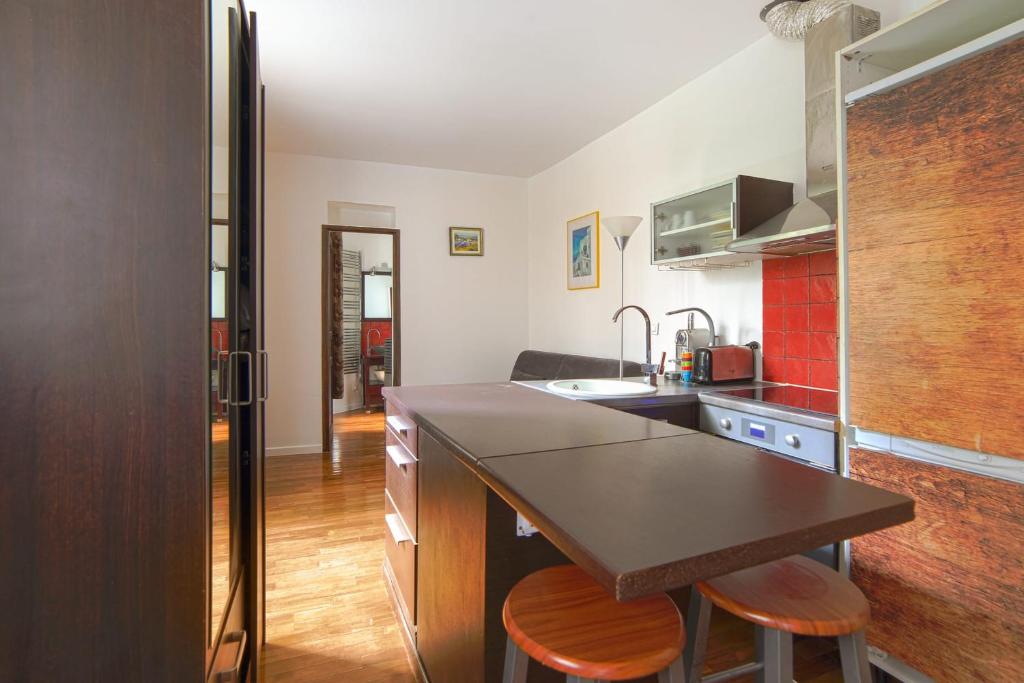 une cuisine avec un comptoir et deux tabourets dans l'établissement Studio Empresa - Welkeys, à Paris