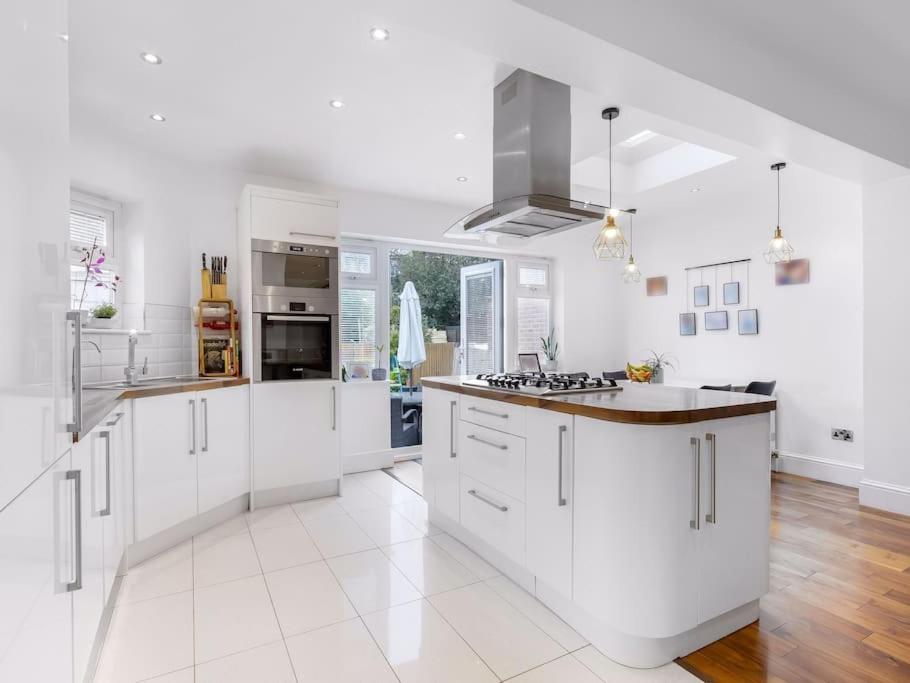 a large kitchen with white cabinets and a counter top at Modern Four bedroom house in Enfield