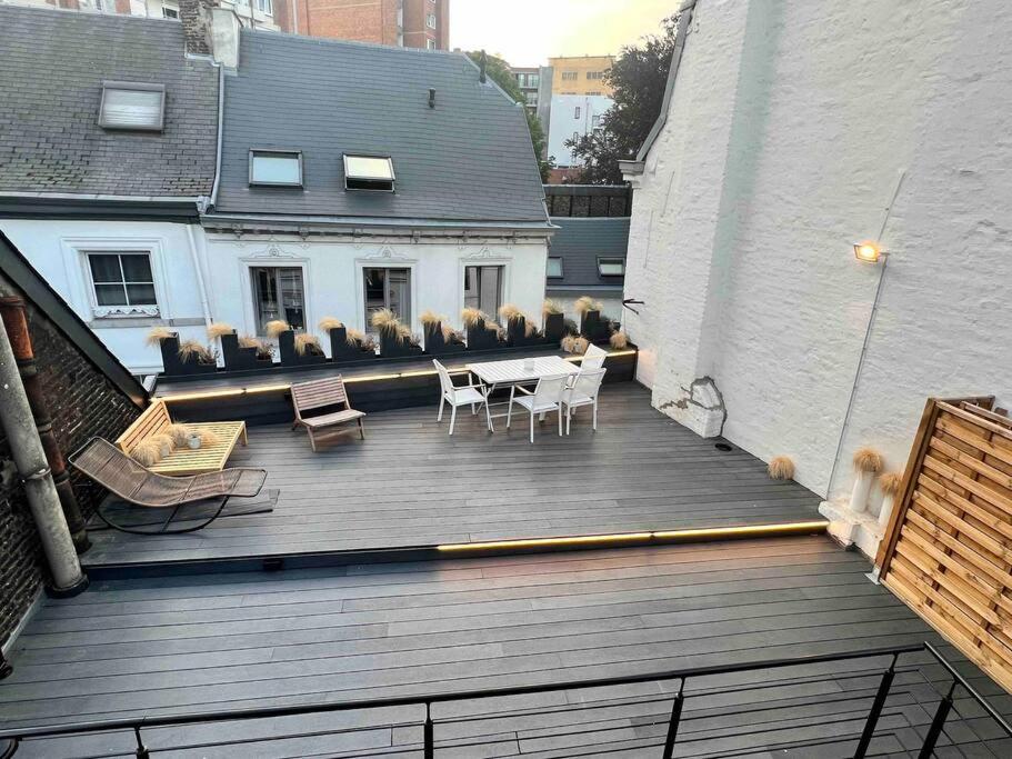 eine Holzterrasse mit Stühlen und einem Tisch auf einem Gebäude in der Unterkunft Maison avec 4 suites & Rooftop - Place Saint Paul in Lüttich