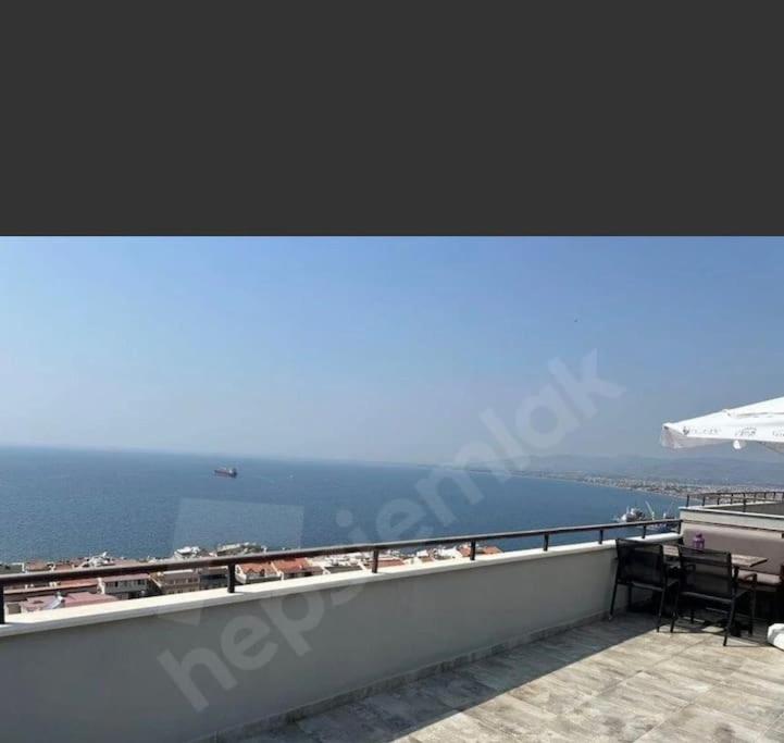 a balcony with a view of the ocean and an airplane at Deniz manzaralı, sessiz konforlu in Dikili