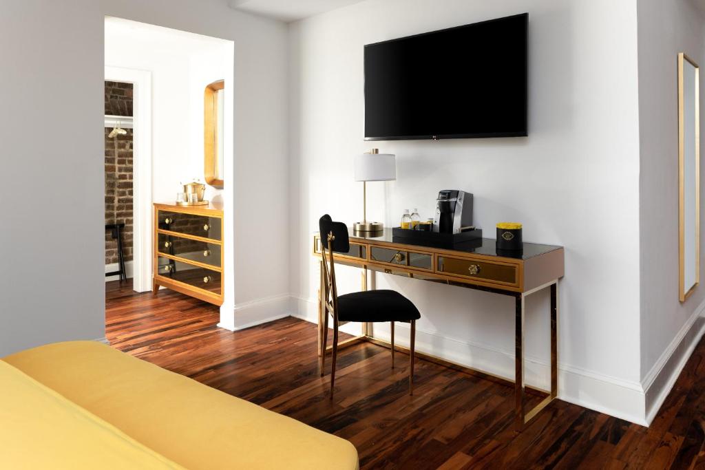 a hotel room with a desk and a television on a wall at The Vendue, Downtown Art Hotel in Charleston