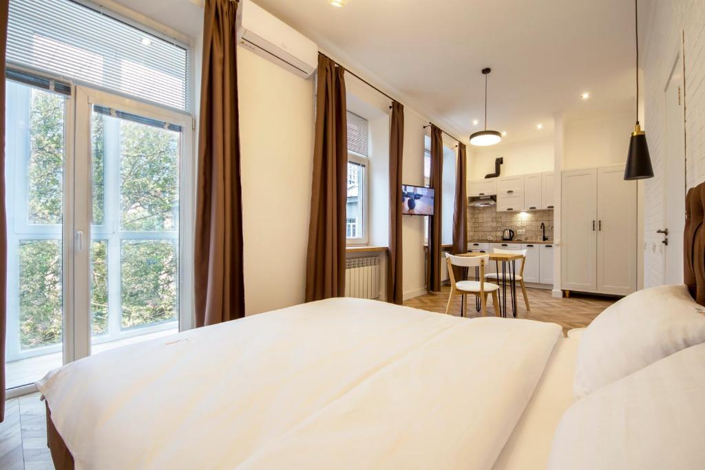 sypialnia z białym łóżkiem i stołem w obiekcie Idea Design Apart-Hotel Chykalenka w Kijowie