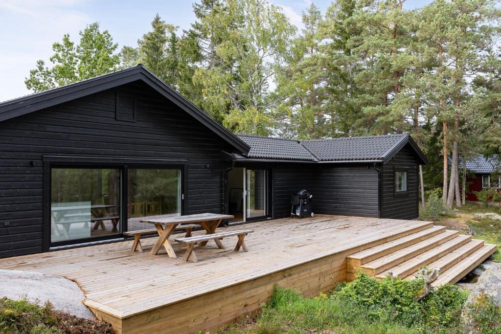 a black house with a wooden deck in front of it at Holiday home on Radmanso, Norrtalje with lake view in Norrtälje