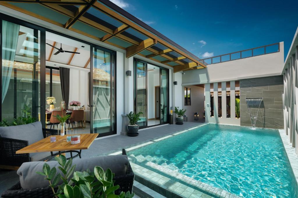 an indoor swimming pool in a house with a table and chairs at Rawayana Central Park Villas in Rawai Beach