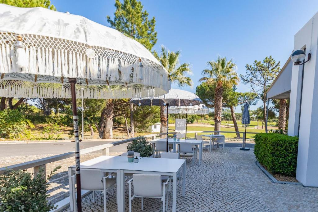 a patio with tables and chairs under umbrellas at Vilar do Golf in Quinta do Lago