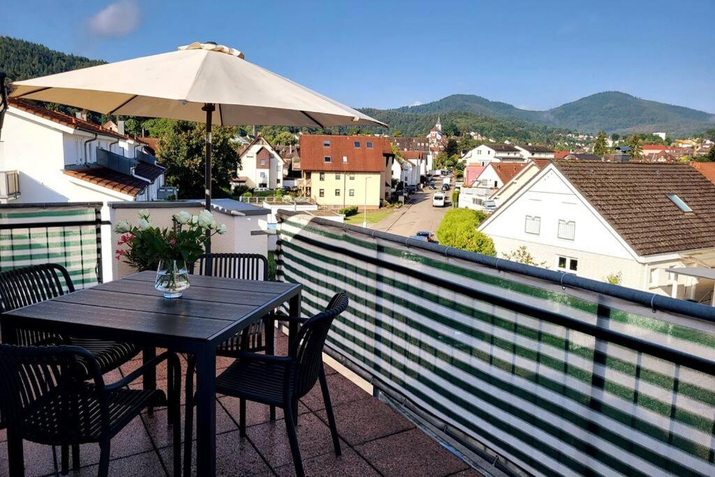 uma mesa e cadeiras numa varanda com um guarda-sol em Ferienwohnung Merkurblick em Gernsbach