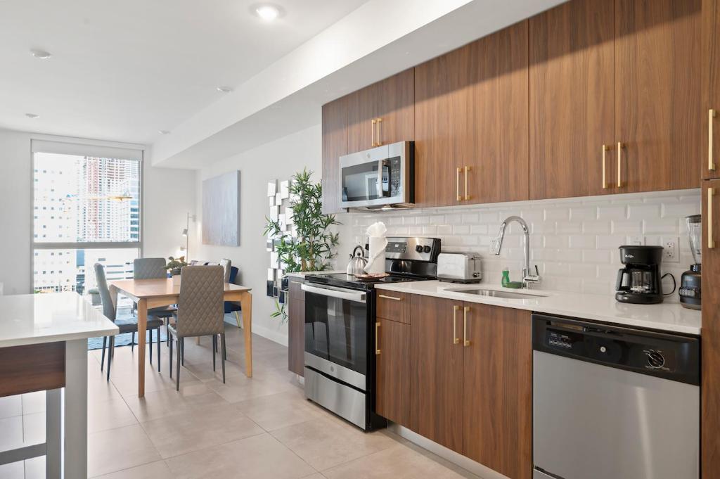 Hotel Modern Unit in Downtown Miami With Free Parking, a kitchen with wooden cabinets and a dining room with a table at Modern Unit in Downtown Miami With Free Parking in Miami