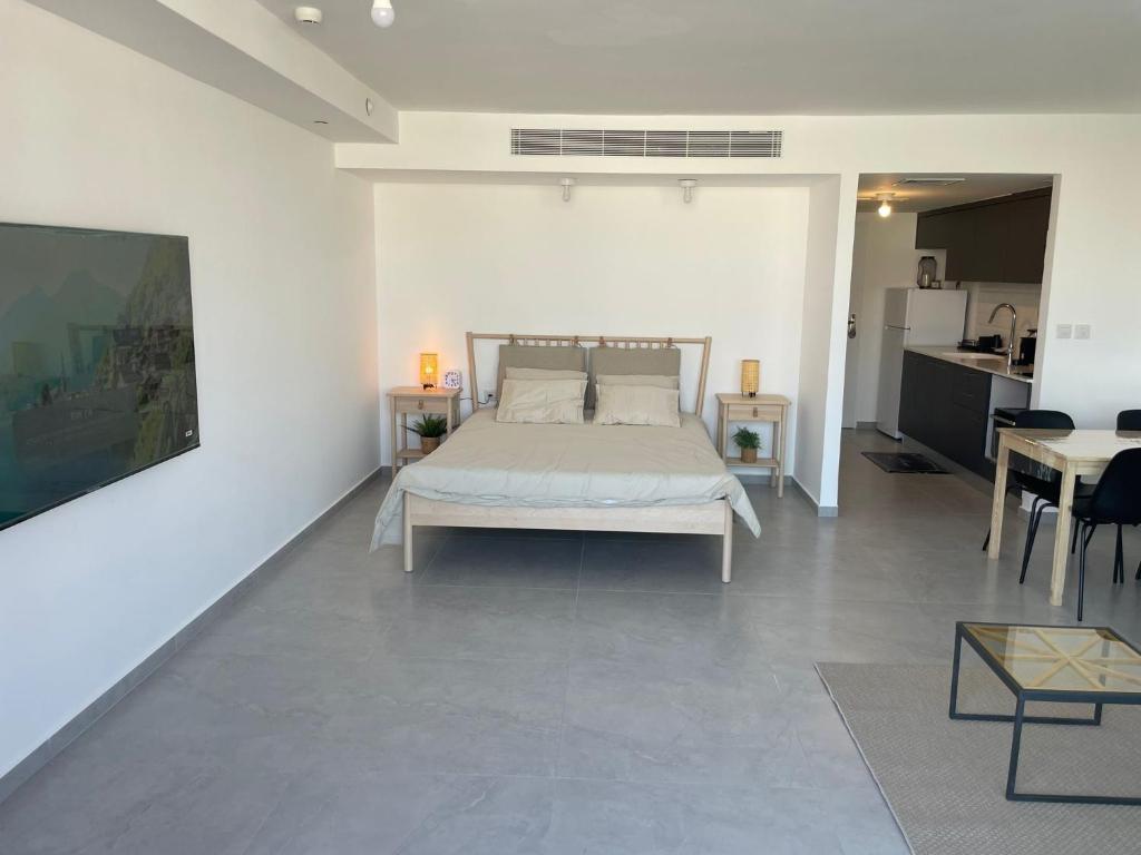 ein weißes Schlafzimmer mit einem Bett und einem Tisch in der Unterkunft oR-Ya Suite in Eilat