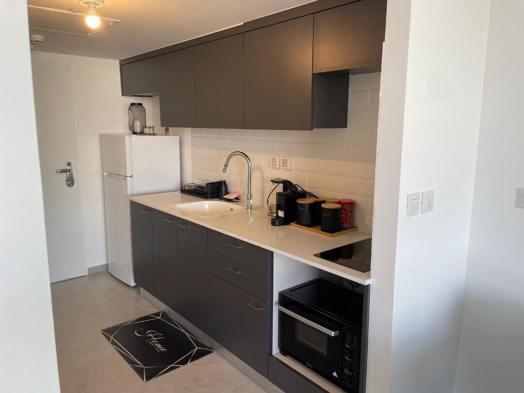 a kitchen with black cabinets and a white refrigerator at oR-Ya Suite in Eilat