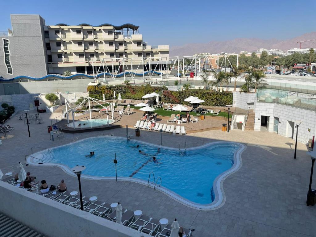 una piscina en un hotel con gente sentada a su alrededor en oR-Ya Suite en Eilat