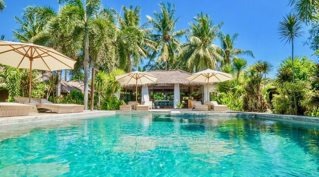a swimming pool at a resort with umbrellas at L'Archipel in Gili Air