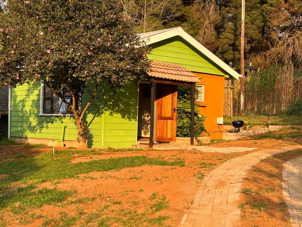 una pequeña casa verde y naranja en un patio en Green Cottage en Haenertsburg