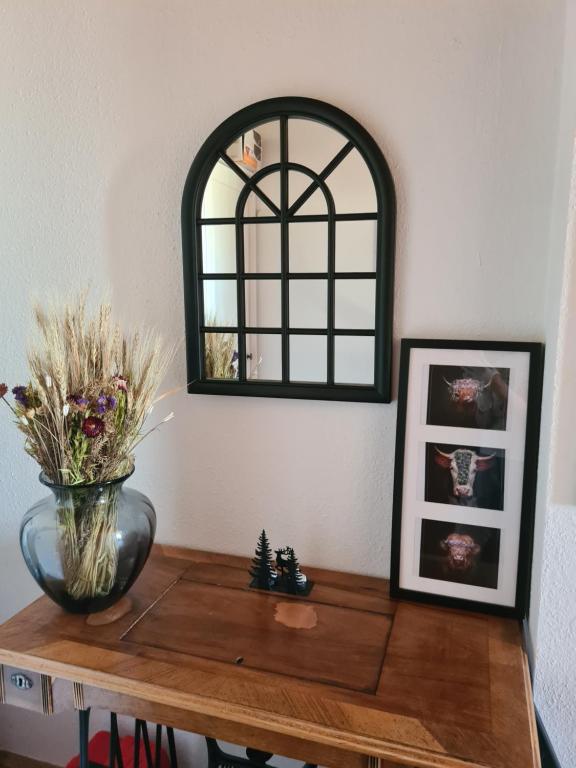 une table avec un vase de fleurs et un miroir dans l'établissement Ferienwohnung Elsa, à Enzklösterle