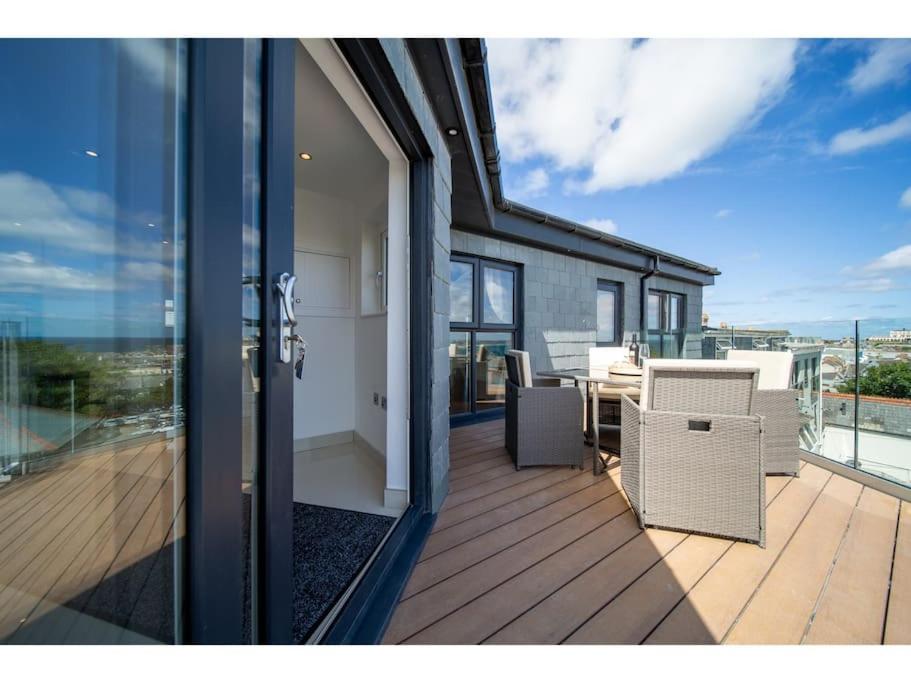 uma varanda de uma casa com uma mesa e cadeiras em Gwel An Keynvor Penthouse em Newquay