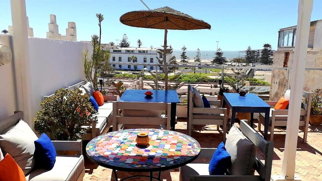 un patio con mesas, sillas y una sombrilla en Riad Ocean Medina, en Essaouira