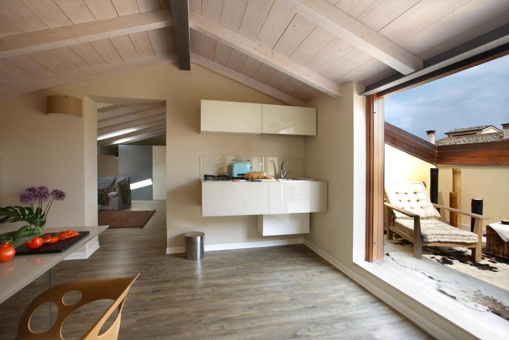 a kitchen with white cabinets and a table and chairs at Corte San Luca Apartments in Bardolino