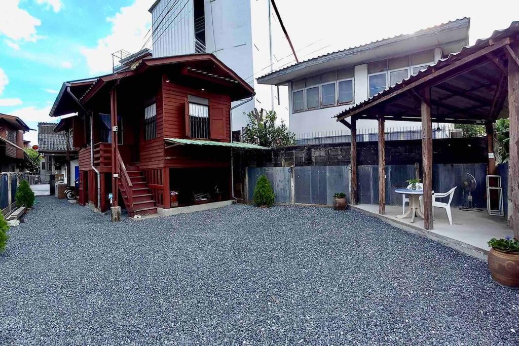 a house with a gravel yard next to a building at Grandma’s House in Chiang Mai