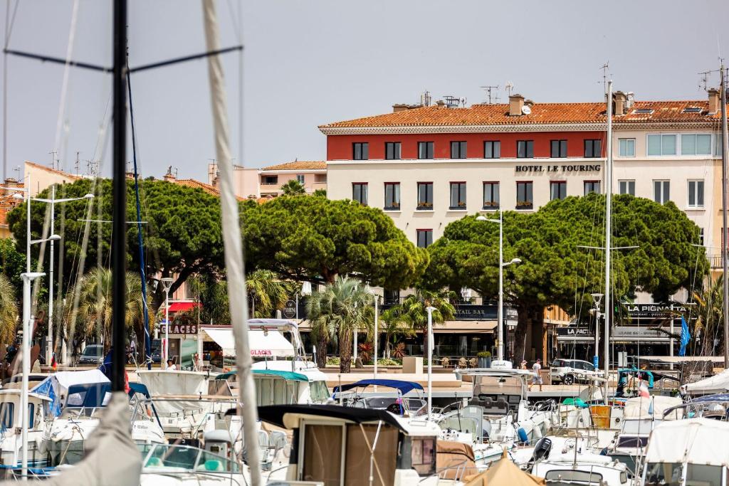 un groupe de bateaux amarrés dans un port avec un bâtiment dans l'établissement Hôtel le Touring, à Saint-Raphaël