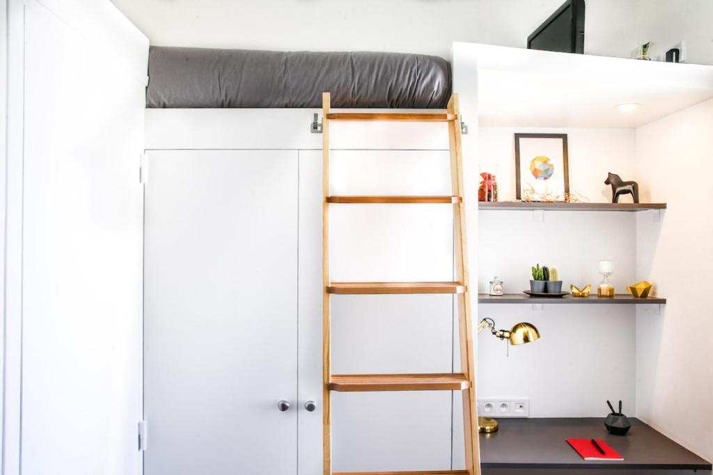 Ce lit superposé se trouve dans un dortoir doté d'une échelle et d'étagères. dans l'établissement Brochant - Cosy studio parc des batignolles, à Paris