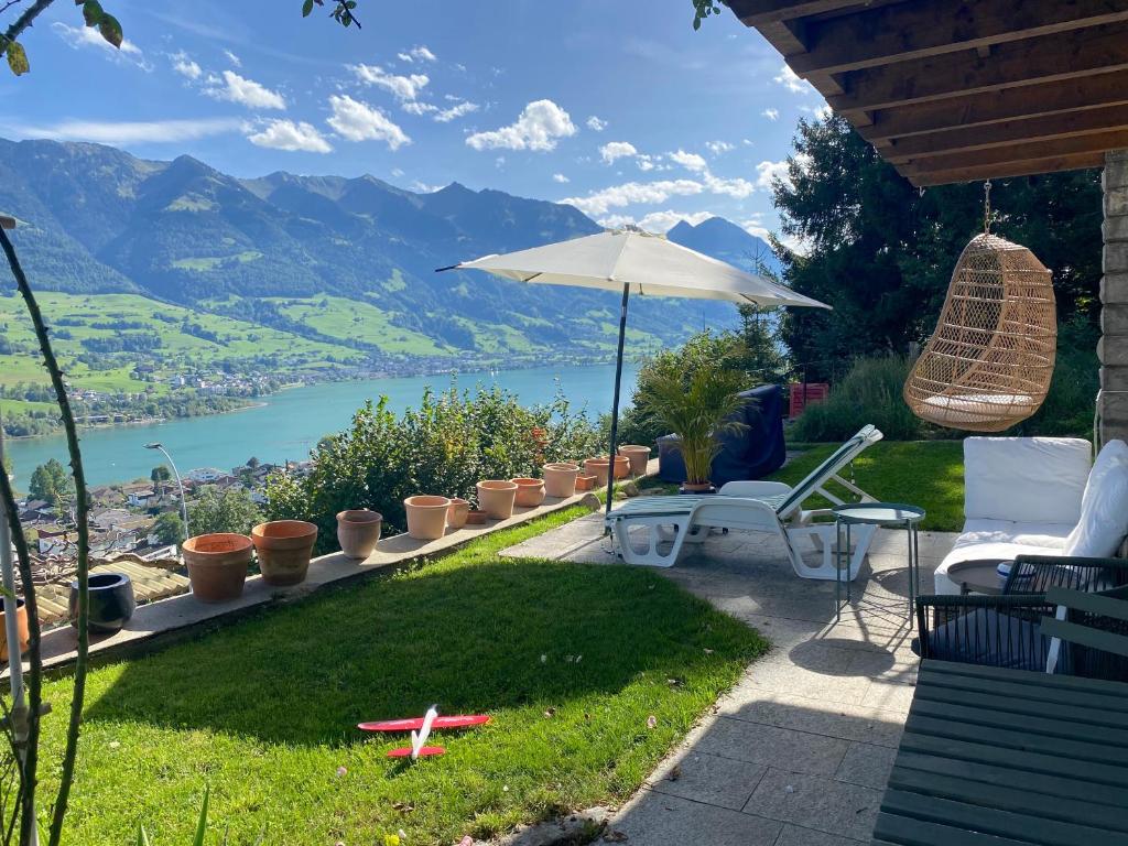 um pátio com cadeiras, um guarda-sol e um lago em Chalet Seeblick em Sarnen