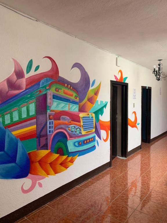 una habitación con una pintura de un autobús en la pared en One Day Trip Hostel en Antigua Guatemala