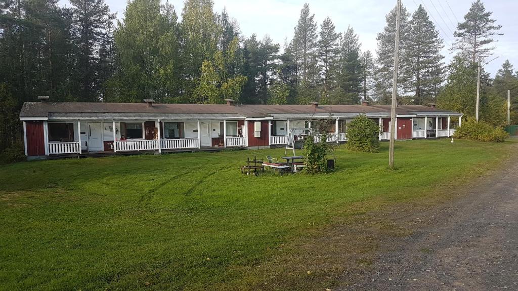 a red and white house with a grass yard at Wanha Kaivoskylä Mainari Oy in Kemijärvi