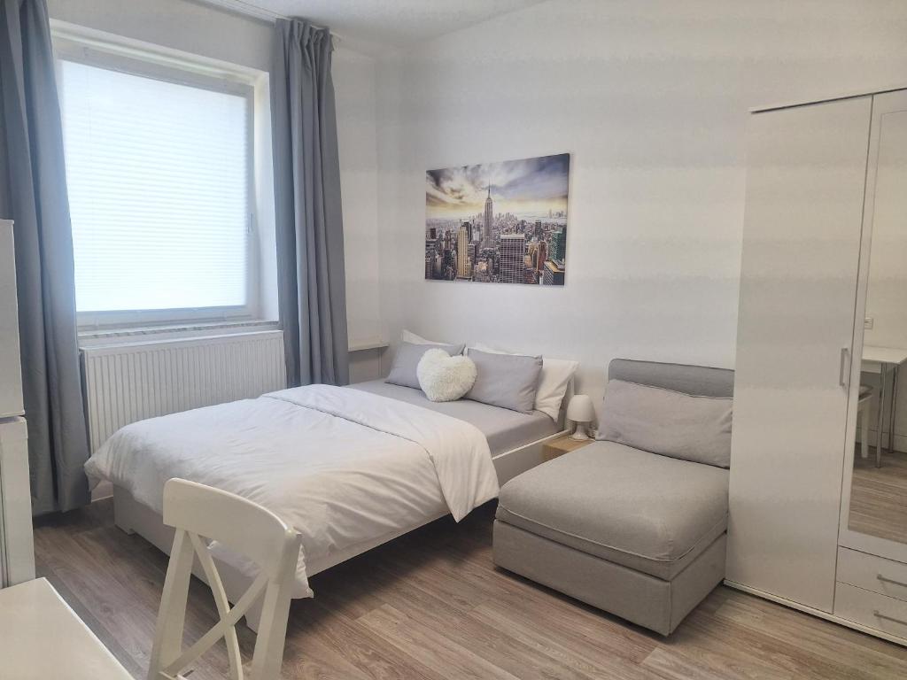 een slaapkamer met een bed, een stoel en een raam bij Studio Apartment 8 in Essen