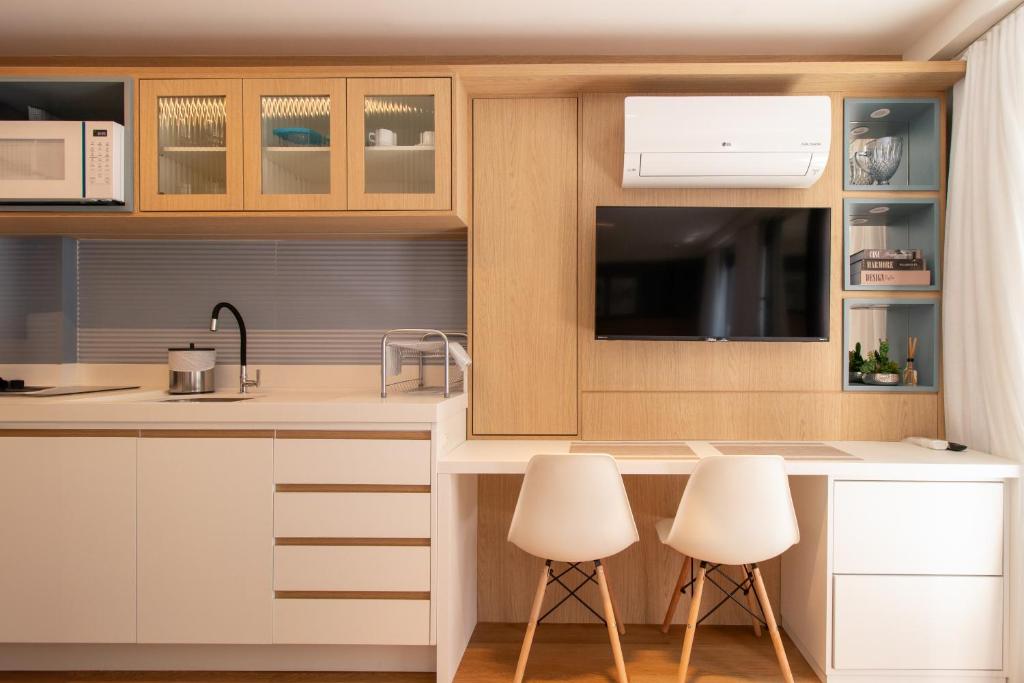 a kitchen with white cabinets and white stools at Luxuoso Studio BF - CWB Central in Curitiba