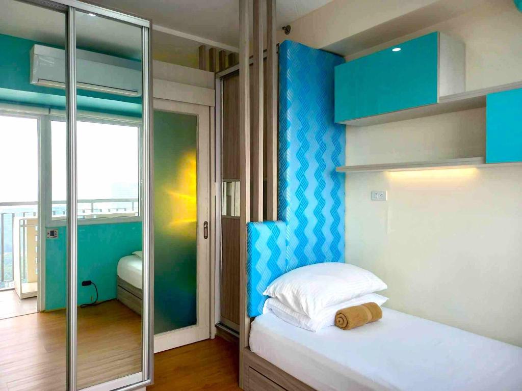 a small bedroom with a bed with a blue wall at Big & Modern Condo with a Wide Balcony & Free Netflix in Manila