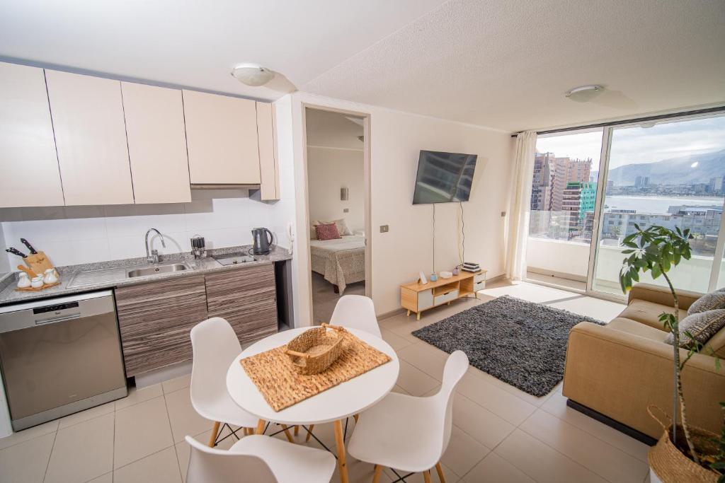 cocina y sala de estar con mesa y sillas en Hermoso departamento en la Peninsula, en Iquique