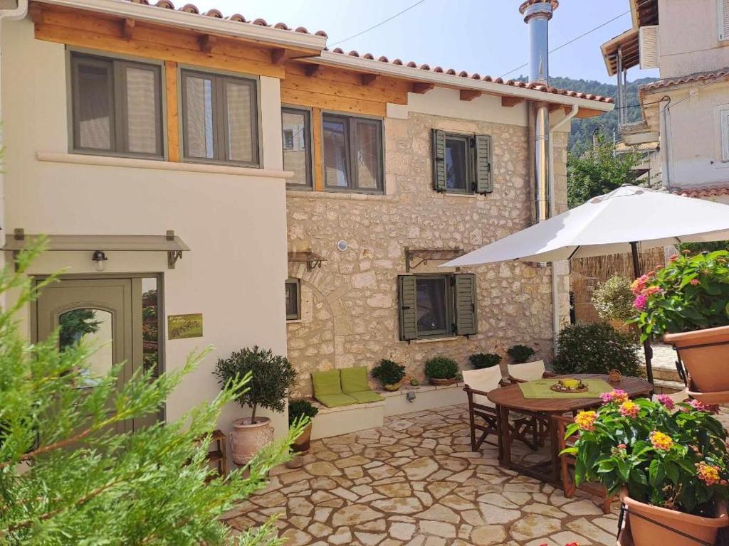 a house with a patio with a table and an umbrella at La casa di Bella a tradional stone house with barbecue in Kariá