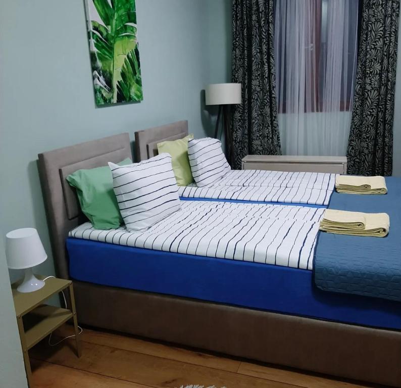 een bed met blauwe en witte lakens en kussens bij Apartman Ana in Leskovac