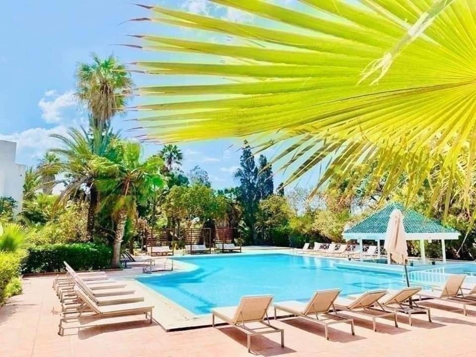 a resort pool with lounge chairs and palm trees at Regency Hammamet in Hammamet Sud