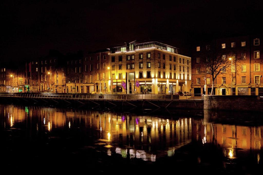 a lit up building next to a river at night at The Morrison Dublin, Curio Collection by Hilton in Dublin