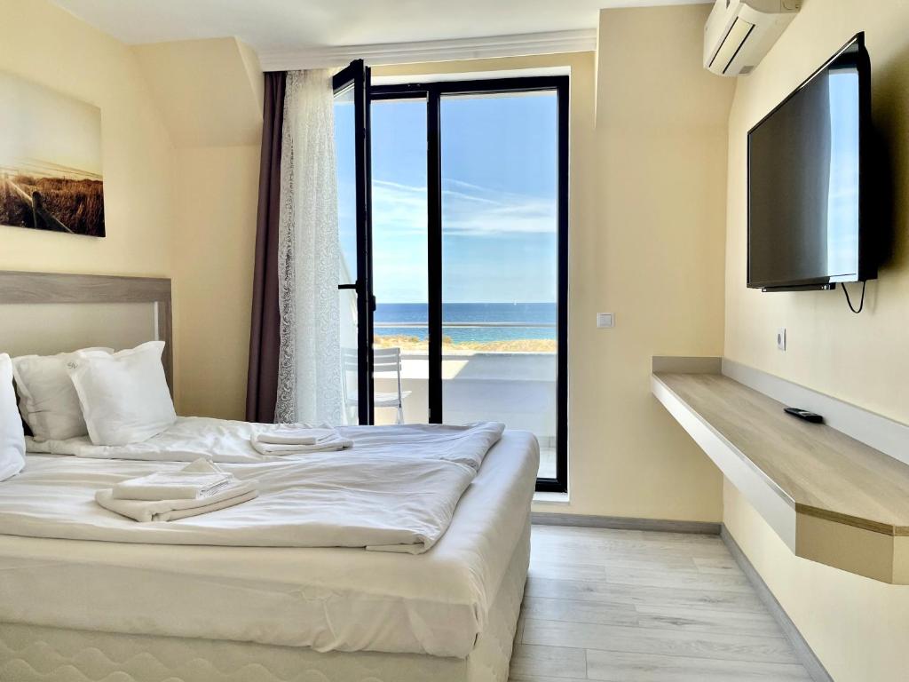 a hotel room with a bed and a large window at APART-HOTEL Stamopolu Lux с изглед към морето in Primorsko