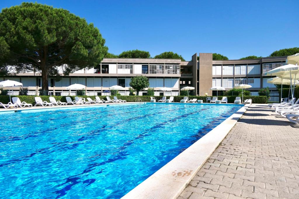 uma grande piscina com cadeiras e guarda-sóis em ISA-Apartment 3 beds in Residence with swimming-pool bed and bath linen included em Marina di Bibbona