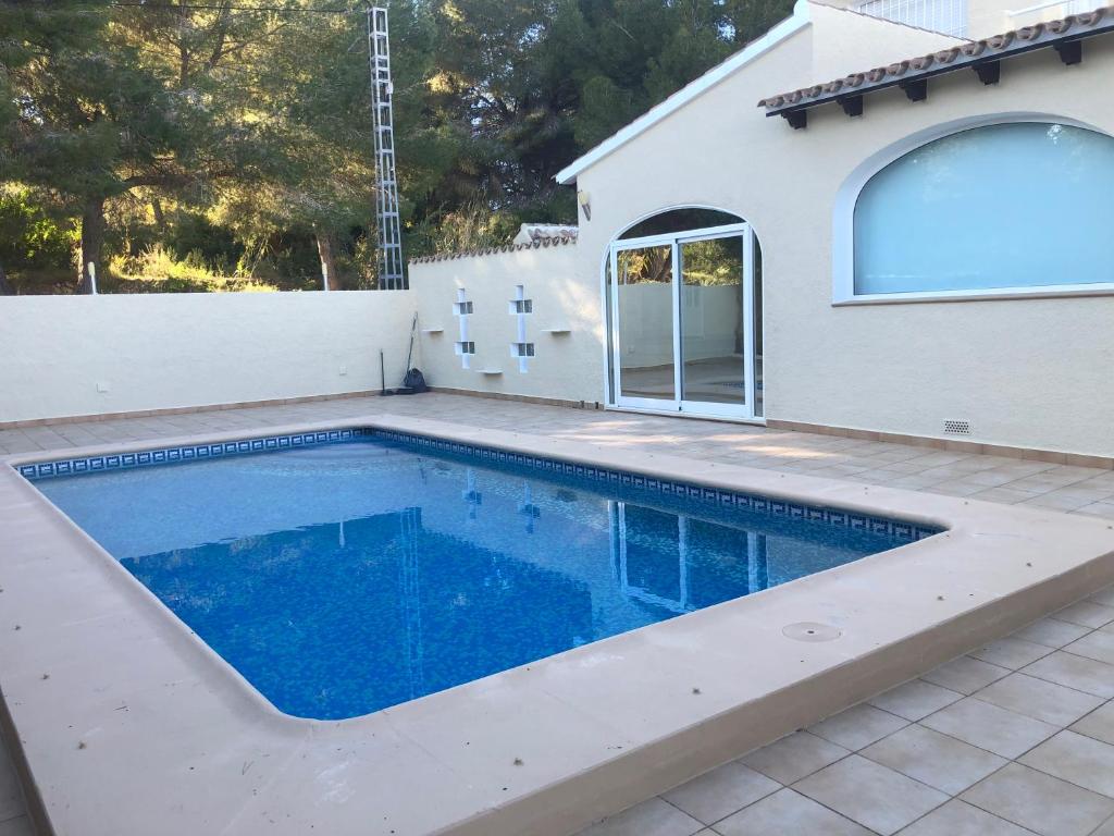 a swimming pool in front of a house at Casa tranquila in Teulada