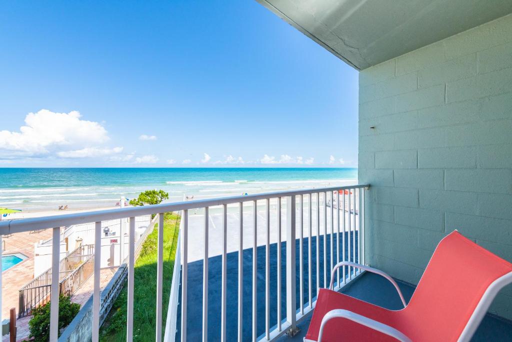 un balcón con un banco rojo y la playa en Direct Oceanfront Private Balcony Tiki King bed, en Daytona Beach