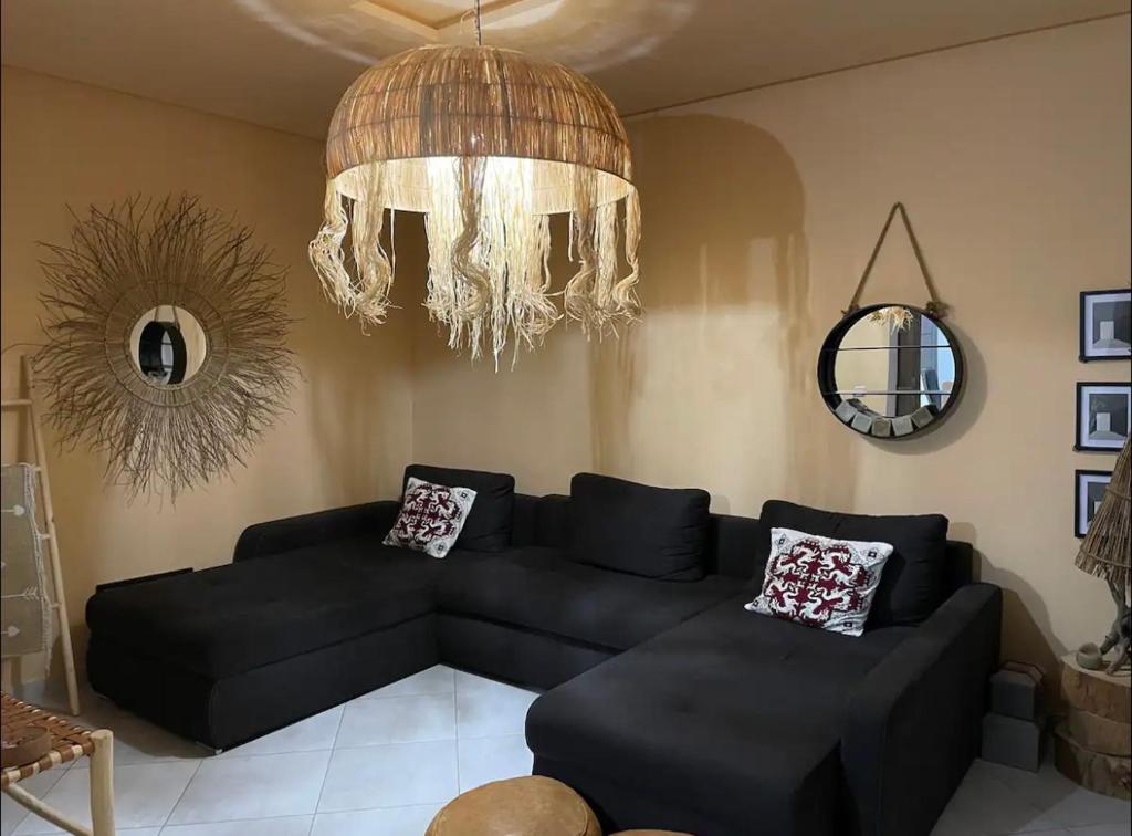salon z czarną kanapą i żyrandolem w obiekcie Cozy appartement w mieście LAl-Ara’isz