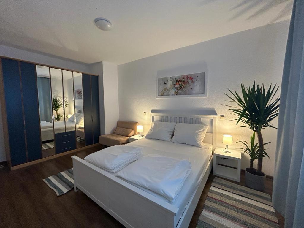 Un dormitorio con una cama blanca y una planta en SkyLineApartment, en Frankfurt