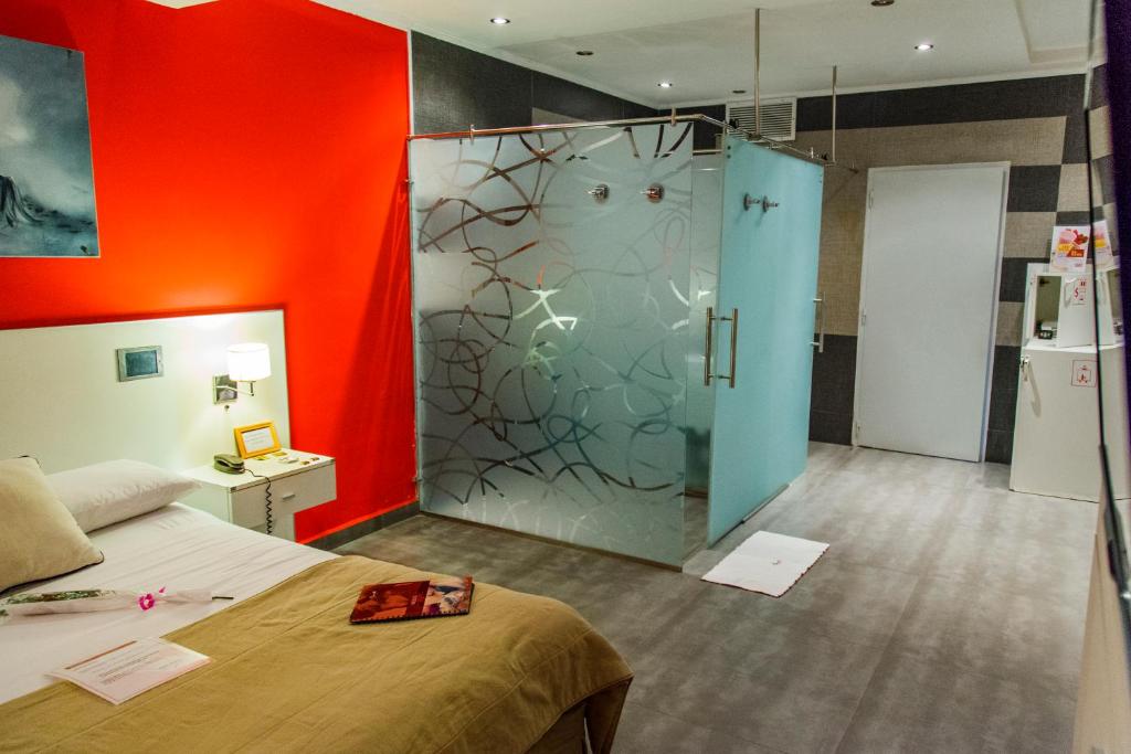 a bedroom with a bed and a glass shower at El Secreto in Comodoro Rivadavia