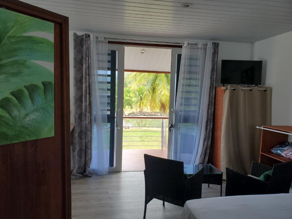 Zimmer mit einem Bett und einer Glasschiebetür in der Unterkunft Fare Mihiau 2 in Hauru