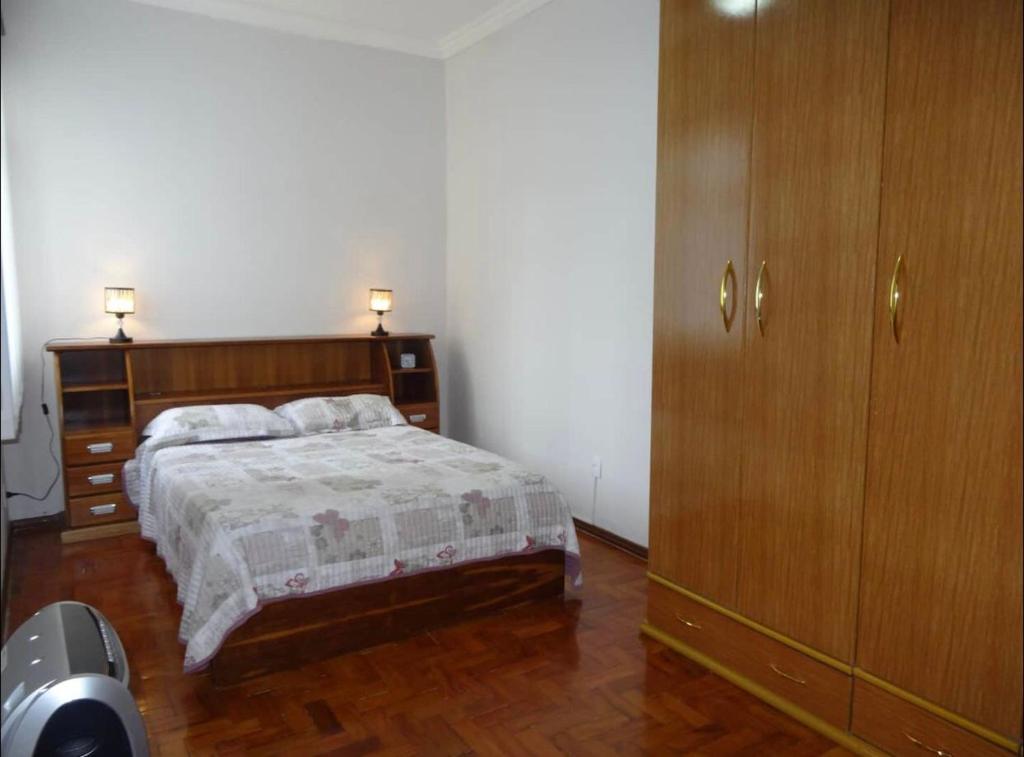 - une chambre avec un lit et une armoire en bois dans l'établissement Espaço exclusivo feminino, à Juiz de Fora