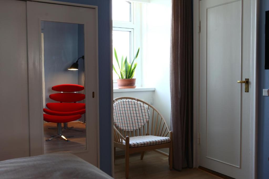 Schlafzimmer mit einem roten Stuhl und einem Spiegel in der Unterkunft Hotel Alexandra in Kopenhagen