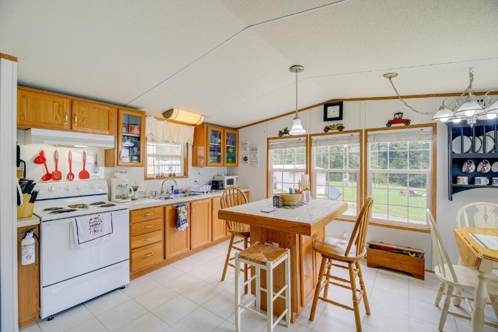 a kitchen with wooden cabinets and a table and chairs at Creekfront Max Meadows Mobile Home with Deck! in Max Meadows