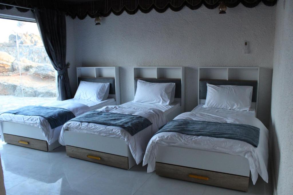 2 aparte bedden in een slaapkamer met een raam bij Al khitaym guest house in Sa‘ab Banī Khamīs