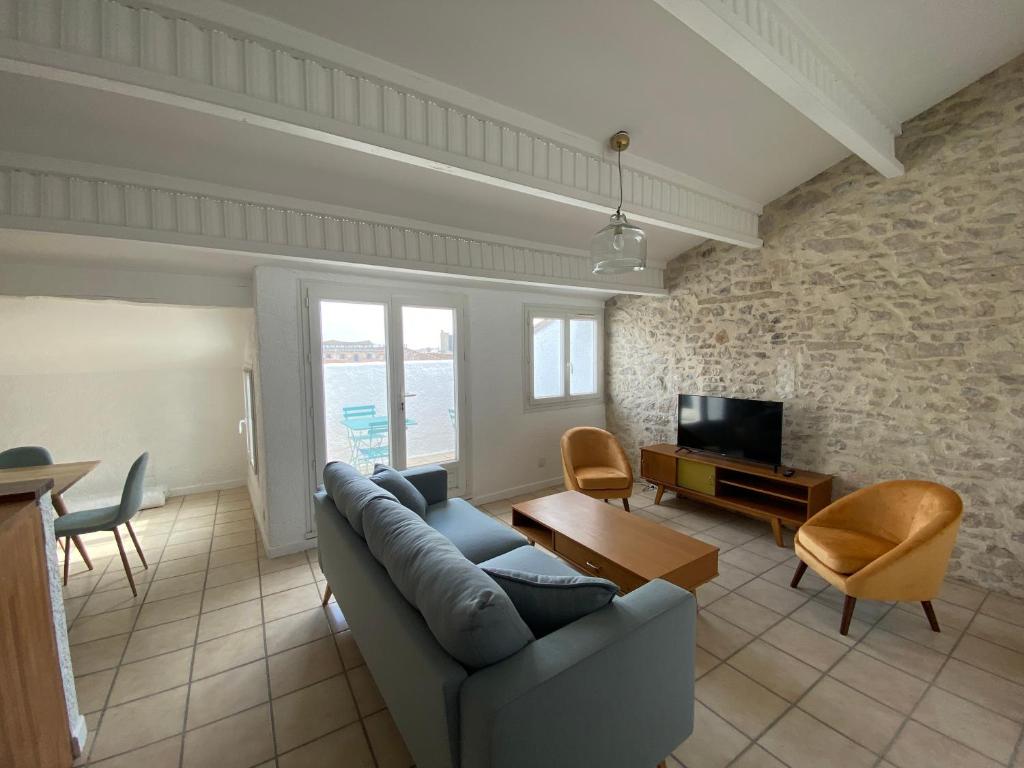 ein Wohnzimmer mit einem Sofa und einem TV in der Unterkunft Duplex de charme avec terrasses in Nîmes