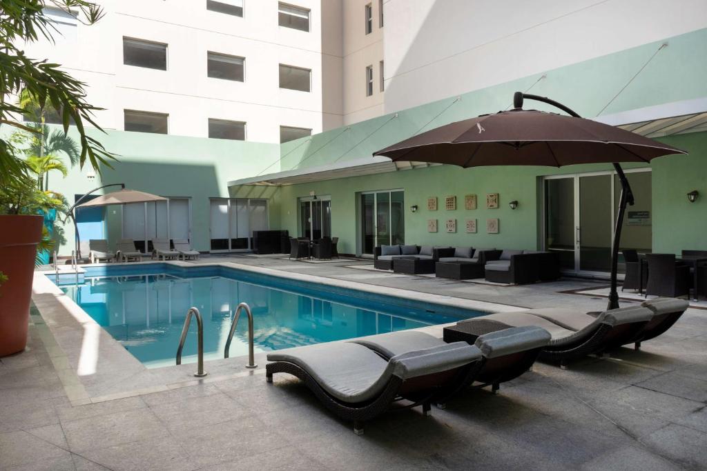 a swimming pool with chairs and an umbrella next to a building at Hampton by Hilton Veracruz Boca Del Rio in Veracruz