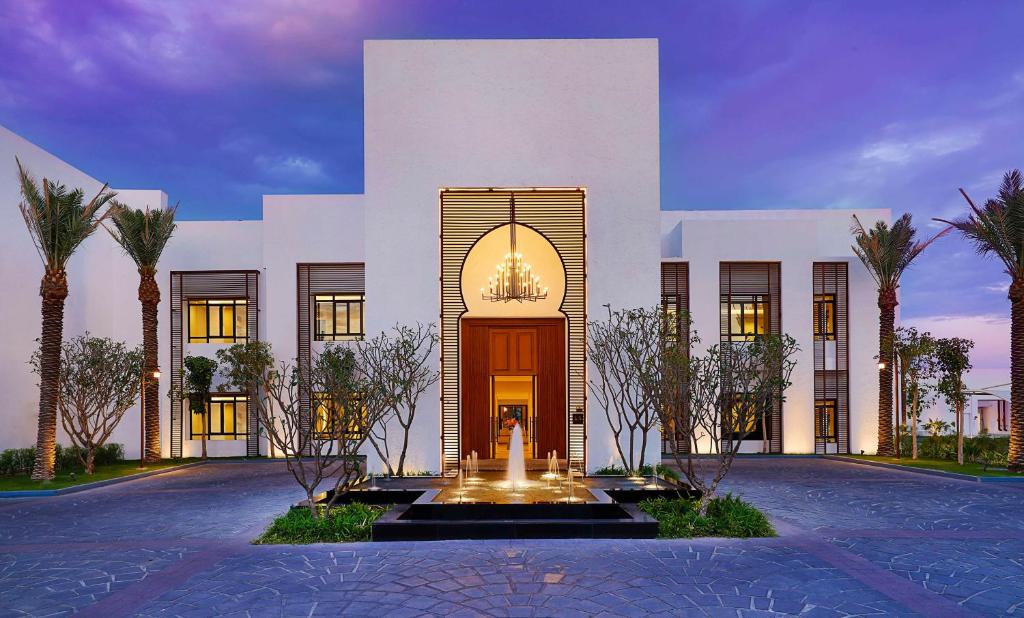 a large white building with a fountain in front of it at Maysan Doha, LXR Hotels & Resorts in Doha